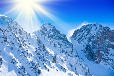 Scenic view of snowcapped mountains against blue sky