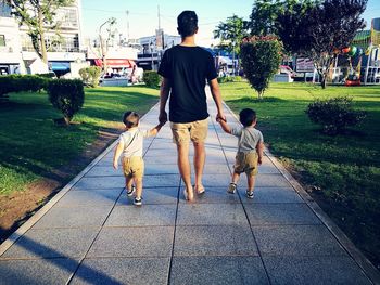 Full length rear view of father walking in park