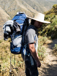 Side view of man wearing hat standing on field