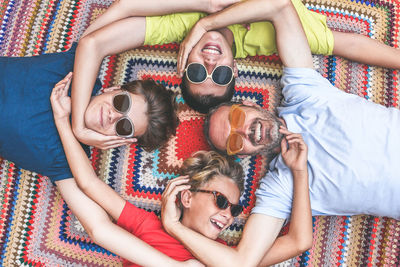 Directly above shot of siblings with father wearing sunglasses while lying on rug