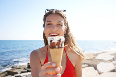 Close-up of beautiful bikini woman holding ice cream cone italian gelato on the beach on summer