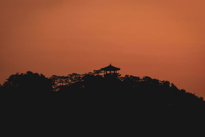 Silhouette built structure against orange sky