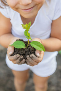 Midsection of girl holding plant in hands cupped