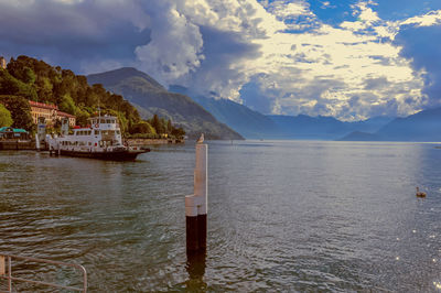 View of lake como in a cloudy day with boat in the foreground in bellagio, italy.