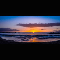 Scenic view of sea against dramatic sky during sunset