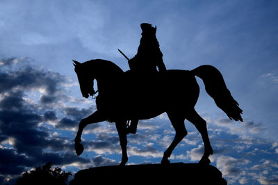 Silhouette of man riding horse