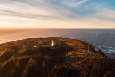 Scenic view of sea and lighthouse against sky during sunset at oregon coast