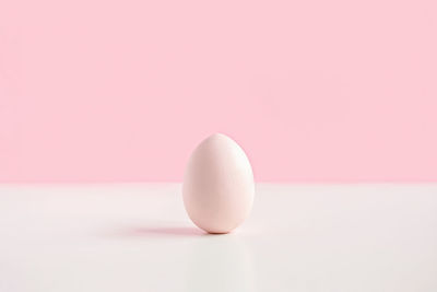 One easter eggs on pink background. easter decoration. side view. poster mock up. simple minimalism