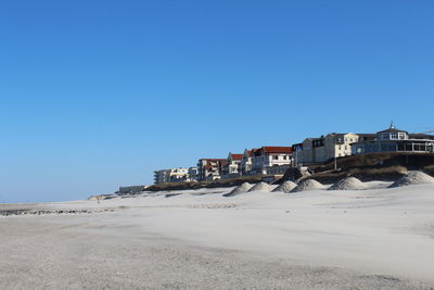 Houses on beach against clear blue sky