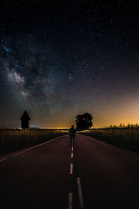 Silhouette man on road against sky at night