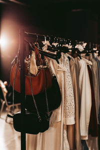 Women's white long dresses and handbags with chains hanging on hangers on the fashion backstage