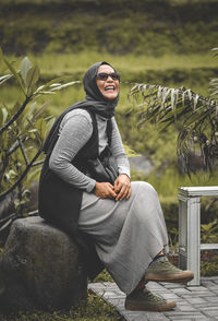 Portrait of young man sitting and laughing in outdoors