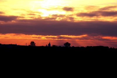 Silhouette trees against dramatic sky during sunset