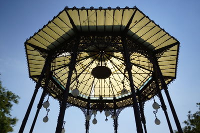 Low angle view of silhouette ferris wheel against clear blue sky