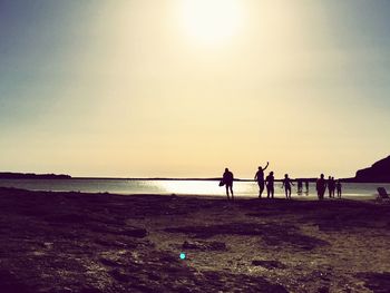 People on beach against sky during sunset