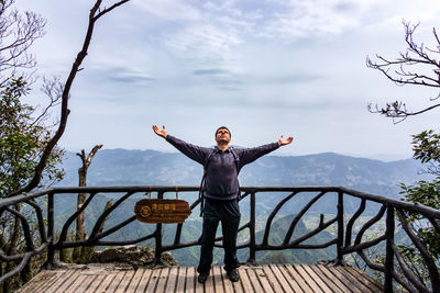 Full length of man standing on railing against sky