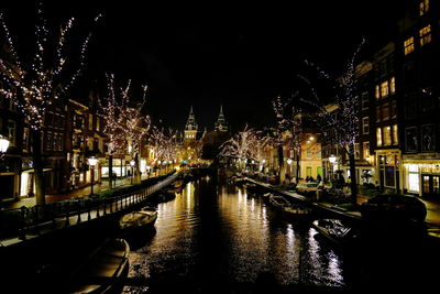 Canal amidst illuminated buildings in city at night