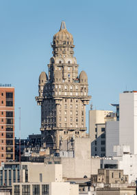 Buildings in city against clear blue sky