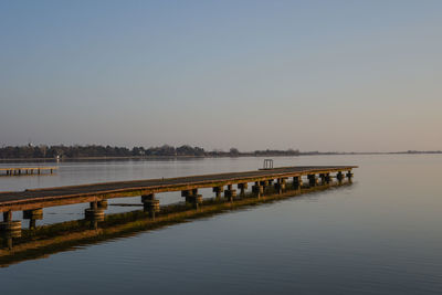 Pier on lake against clear sky during sunset