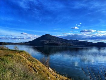 Scenic view of lake and mountains against blue sky