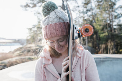 Portrait of a woman looking down holding her skateboard in a skatepark