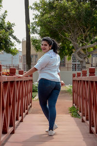 Full length portrait of woman standing on footbridge