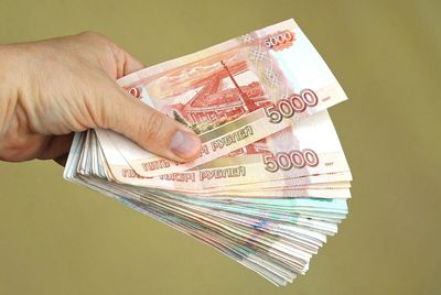 Close-up of hand holding paper currency over beige background