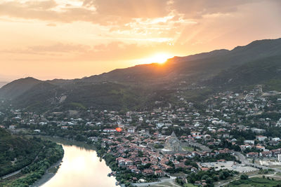 Aerial view of townscape by sea against sky during sunset