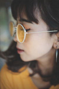 Close-up of young woman wearing sunglasses at home