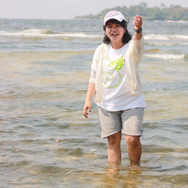 water, beach, sea, person, lifestyles, casual clothing, leisure activity, standing, young adult, shore, full length, front view, vacations, looking at camera, portrait, three quarter length, childhood, happiness