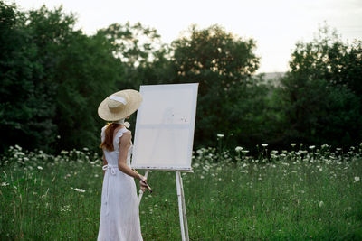 Woman holding umbrella standing on field