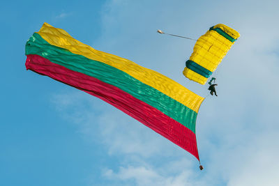 Low angle view of person paragliding against blue sky