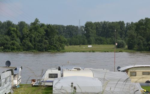 Camping vans by river against sky