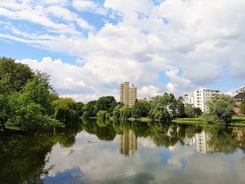 Reflection of trees and buildings in lake against sky