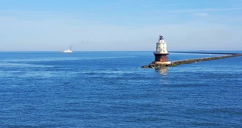 Lighthouse by sea against sky