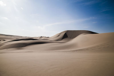 Sand dunes in desert against sky