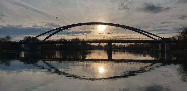 Bridge over river against sky during sunset