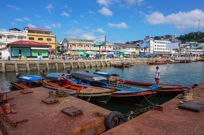 Boats moored at harbor against sky