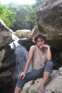 Rear view of man sitting on rock