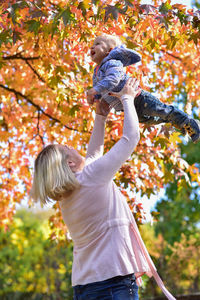 Happy harmonious family outdoors. mother throws her son in the air