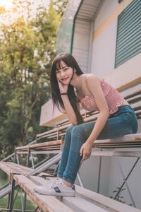 Portrait of woman sitting on railing