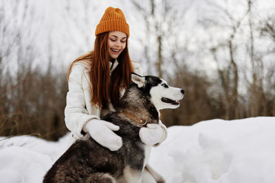 Portrait of woman with dogs on snow covered field