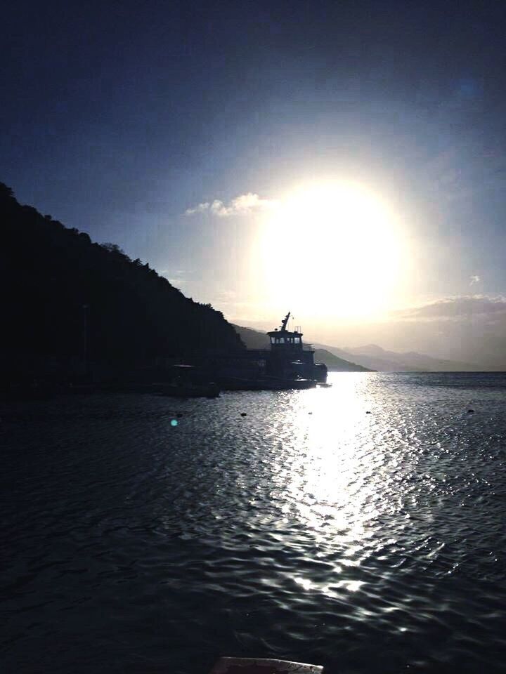 water, waterfront, sun, sea, silhouette, sky, scenics, tranquil scene, tranquility, nautical vessel, beauty in nature, sunlight, reflection, rippled, sunset, nature, sunbeam, transportation, mountain, mode of transport