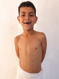 Portrait of smiling boy standing against wall