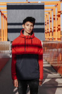 Handsome man wearing hood standing on footbridge