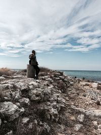 Woman sitting on rock against sea at beach