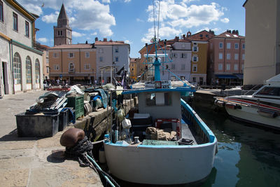 Boats moored at harbor by buildings in city