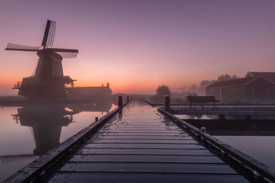 Pier over lake against sky during sunset