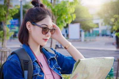 Young woman reading map in city