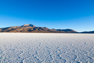 Scenic view of beach against clear blue sky